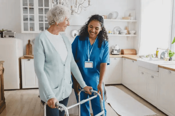 A carer supporting a client with mobility in her kitchen